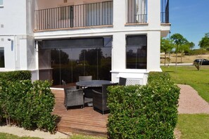Een modern huis met twee verdiepingen, met een overdekte patio voorzien van een ronde tafel en stoelen.