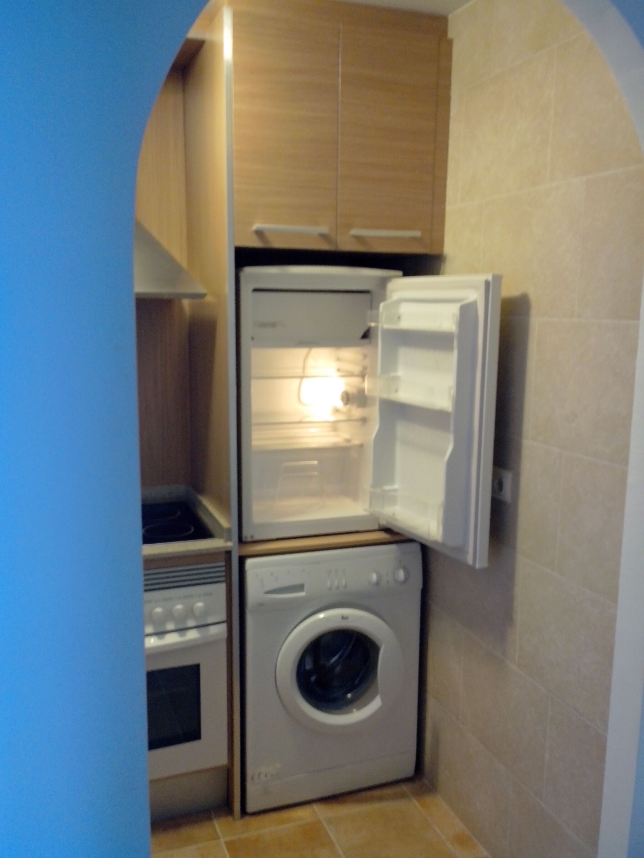 A compact kitchen with a built-in oven, a microwave, and a washing machine.