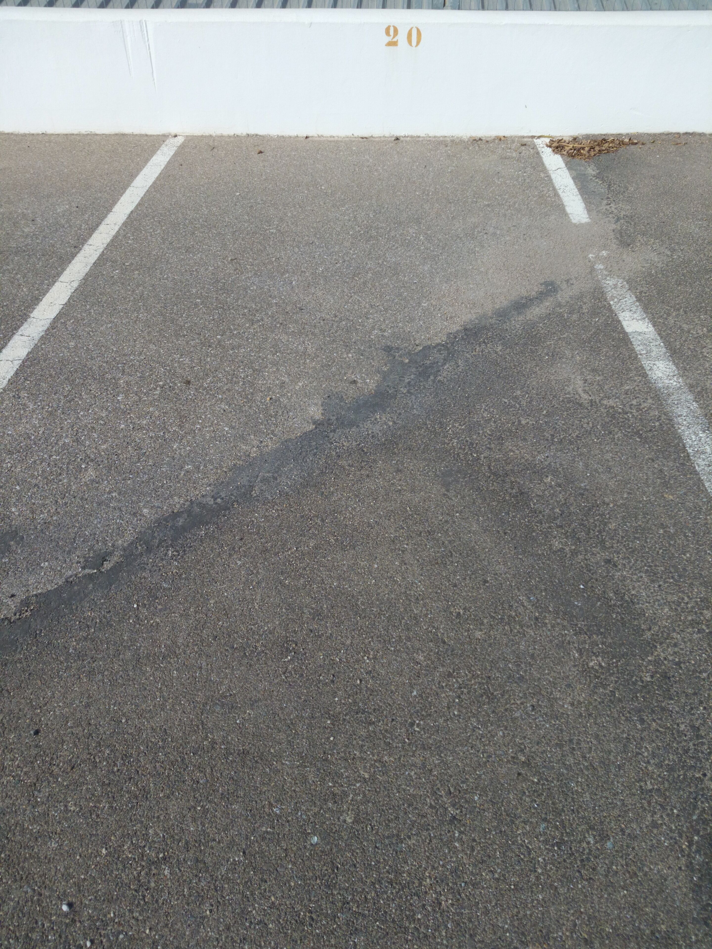Un estacionamiento con líneas blancas y una barrera blanca.