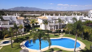 A resort with a swimming pool surrounded by palm trees and a view of mountains.