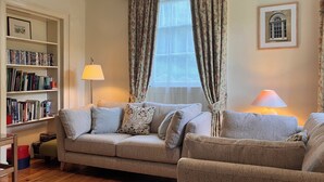 A cozy living room with a sofa, a bookshelf, and a lamp. - Plas yn Yale, Llandegla with mountain views from all windows 4starVisitWales (Denbighshire)