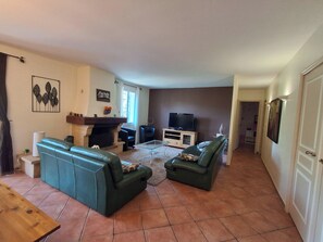 A living room with a fireplace, two green sofas, a television, and a coffee table.