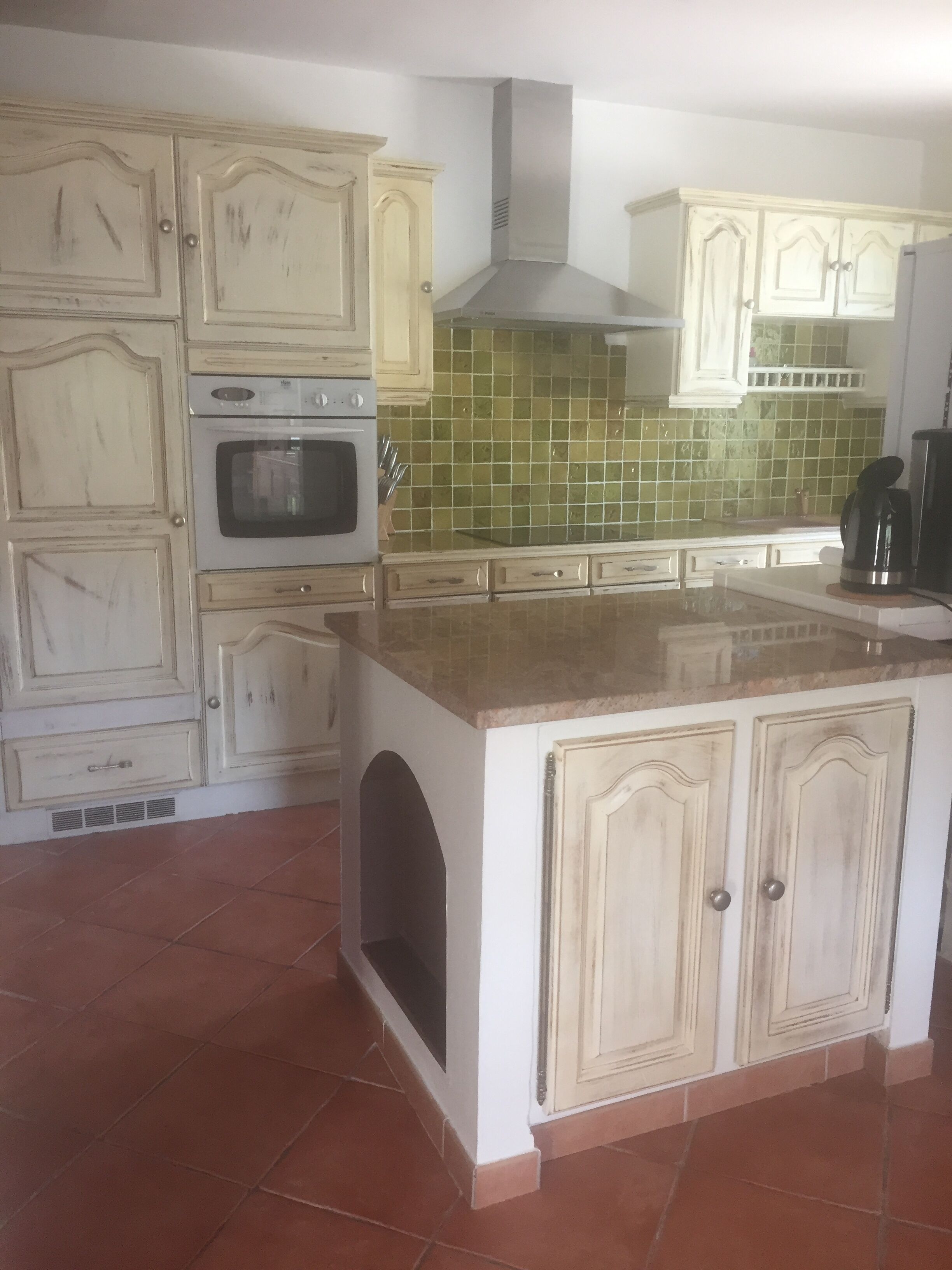 Una cocina con armarios blancos, salpicadero de azulejos y una isla central.