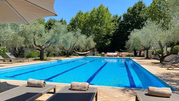 Une piscine avec des chaises longues et un hamac.