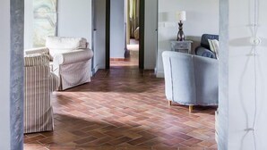 Un couloir intérieur avec un sol carrelé, un canapé, une chaise et une lampe.