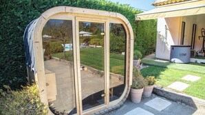 Una struttura in legno con porte vetrate, un vialetto ghiaioso e piante in vaso.