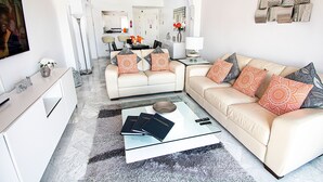 A modern living room with a sofa, coffee table, and a TV. - Stunning Penthouse on Mijas golf course with spectacular mountain views (Malaga)