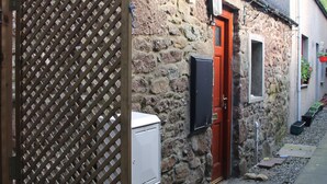 A stone building with a red door, a wooden lattice gate, and a small window. - The Wee Hoose: Probably Scotland's Smallest Holiday Home  (Callander)