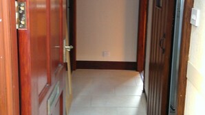 A hallway with wooden doors, a tiled floor, and a small rug. - The Wee Hoose: Probably Scotland's Smallest Holiday Home  (Callander)