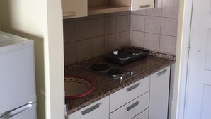 A compact kitchen with white cabinets, a granite countertop, and a built-in stove. - Panoramic studio next to the beach (Giardini Naxos)