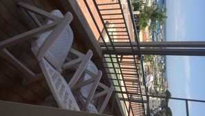A view from a balcony overlooking a marina with boats, a clear sky, and a distant cityscape. - Panoramic studio next to the beach (Giardini Naxos)