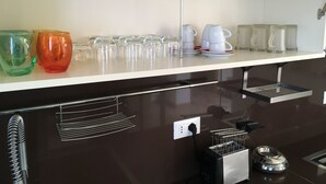 Eine Küchenarbeitsplatte mit unterschiedlichem Glasgeschirr, darunter Tassen und eine Kaffeekanne.