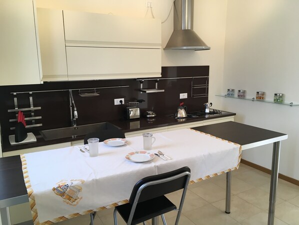 Una cocina moderna con una mesa de comedor preparada para dos personas, equipada con tetera, platos y cubiertos.