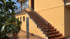 Ein Gebäude mit einer Treppe, die zu einem Balkon, einer Tür und einem Blumentopf führt.