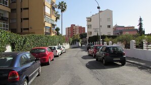 A street with parked cars, a building with balconies, and a clear sky. - Studio Apartment, Sleeps 2. Centrally located & close to all amenities. (Benalmádena)