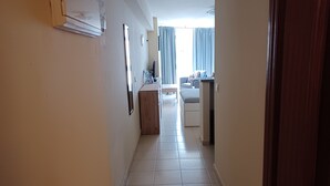 A hallway with a bed, a desk, and a window with curtains. - Studio Apartment, Sleeps 2. Centrally located & close to all amenities. (Benalmádena)