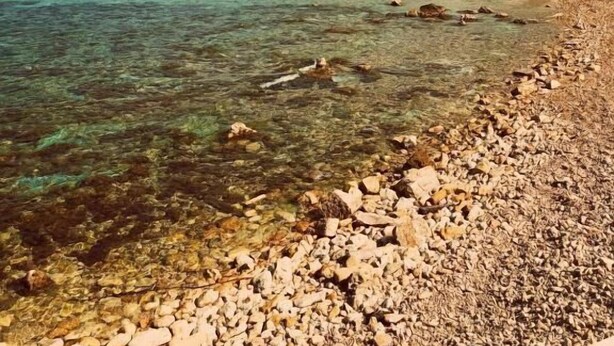 A rocky beach with clear turquoise water and a large rock formation in the background. -  Apartment with balcony and sea views, fully A/c (Marsalforn)
