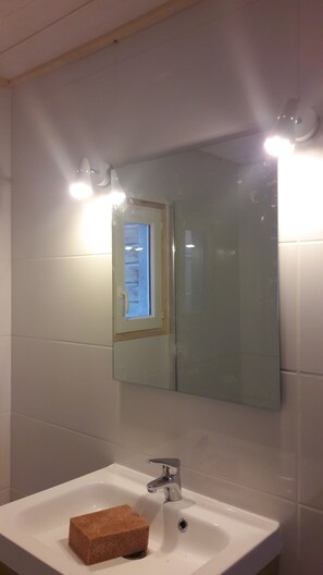 A bathroom with a white sink, a mirror, and a window.