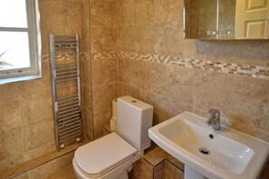 Une salle de bain équipée de toilettes, d’un lavabo et d’un porte-serviettes.