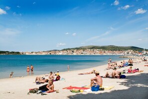 A beach with people sunbathing and swimming.