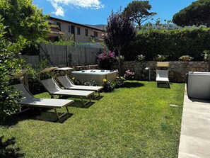 Ein Garten mit Whirlpool, Liegestühlen und einer Steinmauer.
