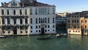 A historic building with multiple stories and arched windows, located next to a canal with gondolas.