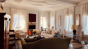 A spacious living room with a fireplace, comfortable seating, and large windows with curtains.