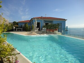 Une piscine avec des chaises longues et vue sur la mer.