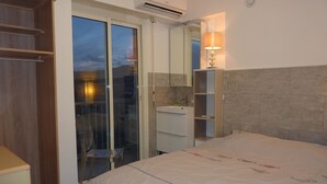 A bedroom with a bed, a bathroom, and a sliding glass door leading to a balcony. - Magnificent apartment T3 sea view 180 degrees, Sea at 20 meters (Le Lavandou)