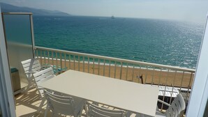 A balcony with a table and chairs, overlooking a beach and the sea. - Magnificent apartment T3 sea view 180 degrees, Sea at 20 meters (Le Lavandou)