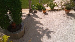 Un jardin bien entretenu, avec une pelouse circulaire, des allées de gravier et des plantes en pot.