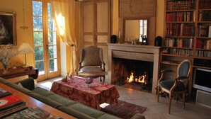 Un salon chaleureux avec une cheminée, une bibliothèque et un coin salon confortable.