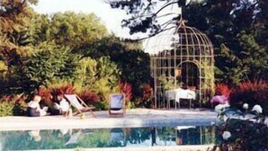 Un espace piscine agrémenté d’une structure en forme de cage à oiseaux, de chaises longues et d’une petite table.