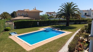 A rectangular swimming pool with a tiled deck, surrounded by well-maintained grass and palm trees. - Lovely Apartment, Ponta da Piedade Natural Reserve, Camilo Beach, Dona Ana Beach (Lagos)