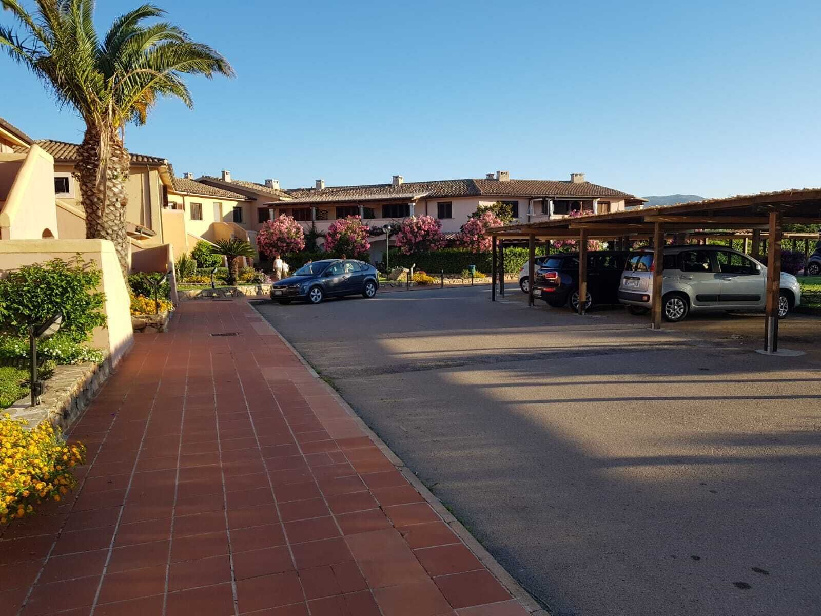 Un quartier résidentiel doté d’une promenade dallée, de voitures garées et d’un parking couvert.