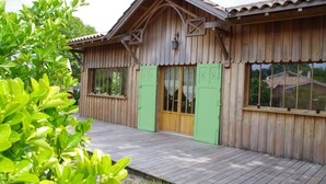 A wooden building with a sloped roof, green shutters, and a wooden deck. - Cap Ferret charming wooden villa (Lège-Cap-Ferret)