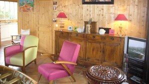 A wooden interior with two colorful chairs, a wooden cabinet with decorative items, and a framed painting on the wall. - Cap Ferret charming wooden villa (Lège-Cap-Ferret)