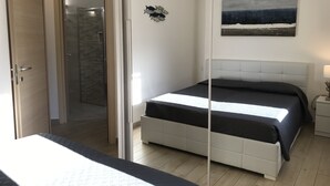 Une chambre à coucher avec un lit, une porte donnant sur une salle de bain et un tableau accroché au mur.