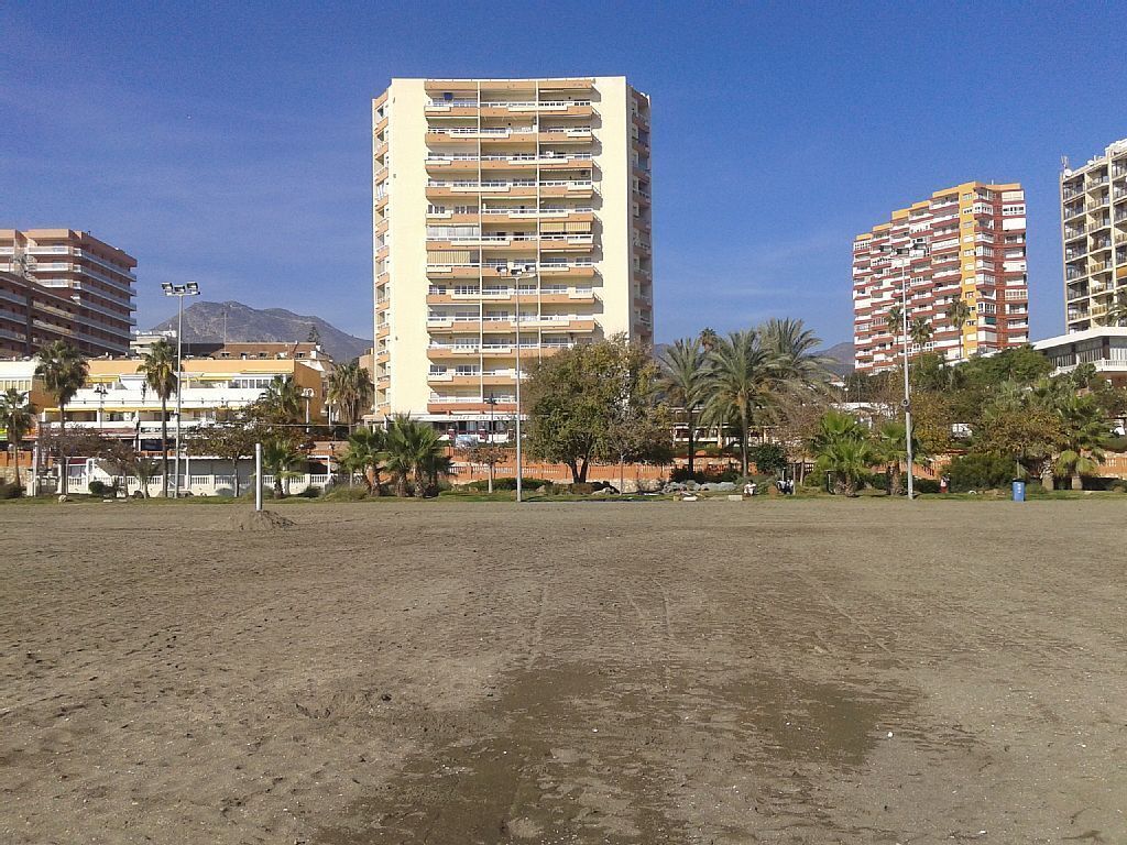 Een zandstrand met gebouwen op de achtergrond.