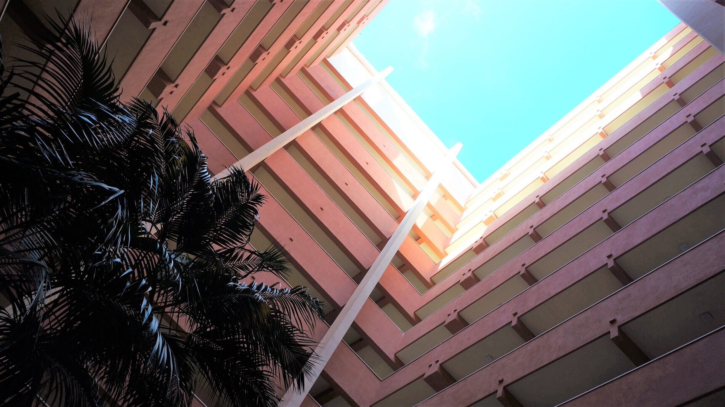A high-rise building with a clear sky view, featuring a modern architectural design with horizontal lines and a central white column.