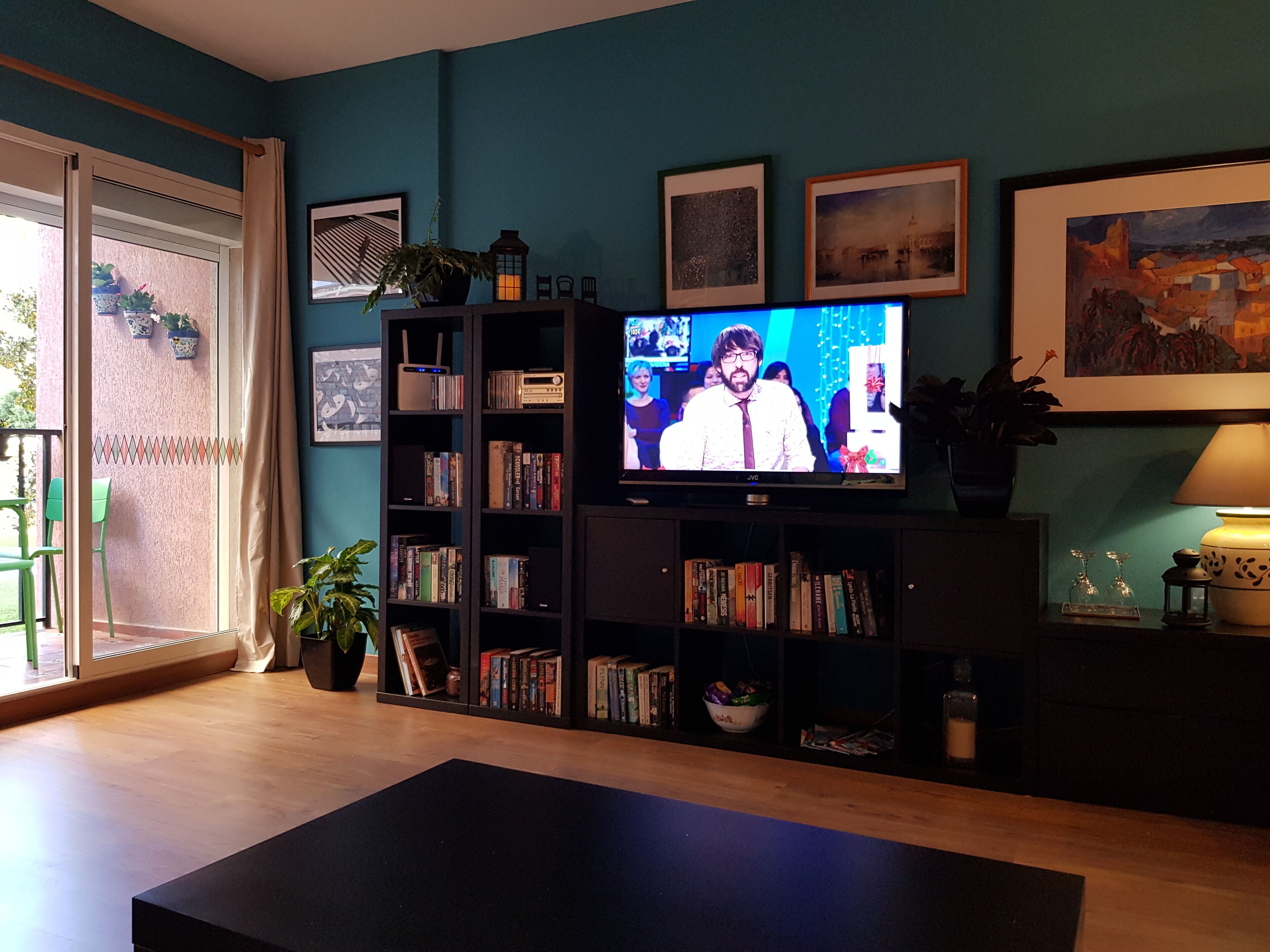 A living room with a television, bookshelves, and a green chair.