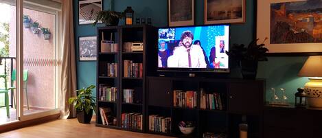 A living room with a television, bookshelves, and a green chair.
