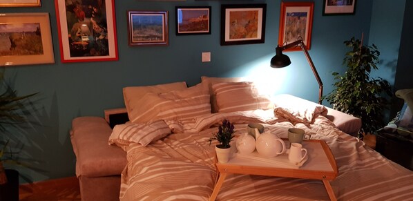 A bedroom with a bed, a bedside table, a lamp, and a tray with tea set.