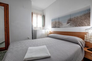 A neatly made bed with a white pillow, a wooden headboard, and a wall-mounted painting of a beach scene. - Apartment/ flat - Cullera (Cullera)
