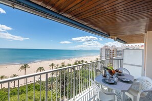 A balcony with a view of a beach and ocean, a table set for dining, and a railing. - Apartment/ flat - Cullera (Cullera)