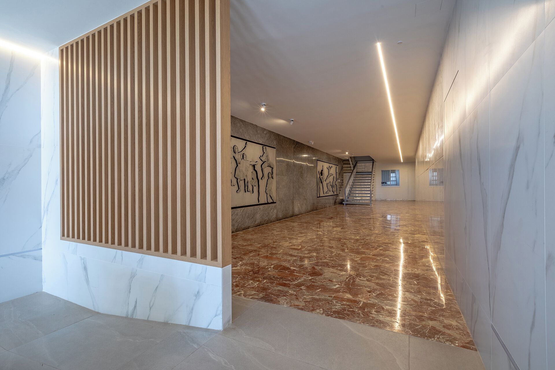 Un vaste hall d’entrée doté d’un sol en marbre, d’une cloison en bois et d’œuvres d’art accrochées aux murs.