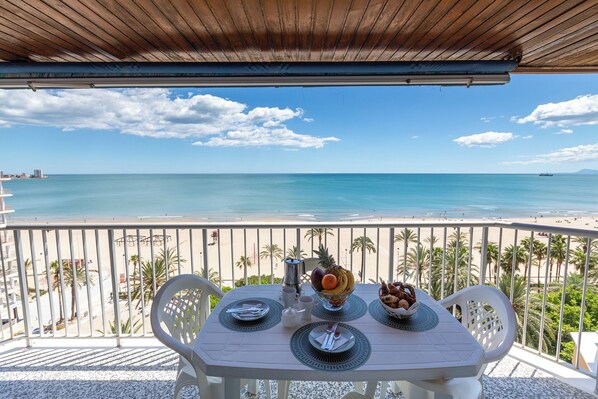 A balcony with a table set for breakfast, overlooking a beach with clear blue water and a few boats. - Apartment/ flat - Cullera (Cullera)