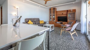 A modern living room with a dining table, sofa, chairs, a TV, and a wooden cabinet. - Apartment/ flat - Cullera (Cullera)