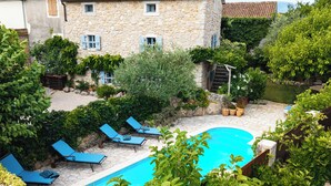 Un edificio in pietra con tetto in tegole, una piscina e poltrona da relax blu.