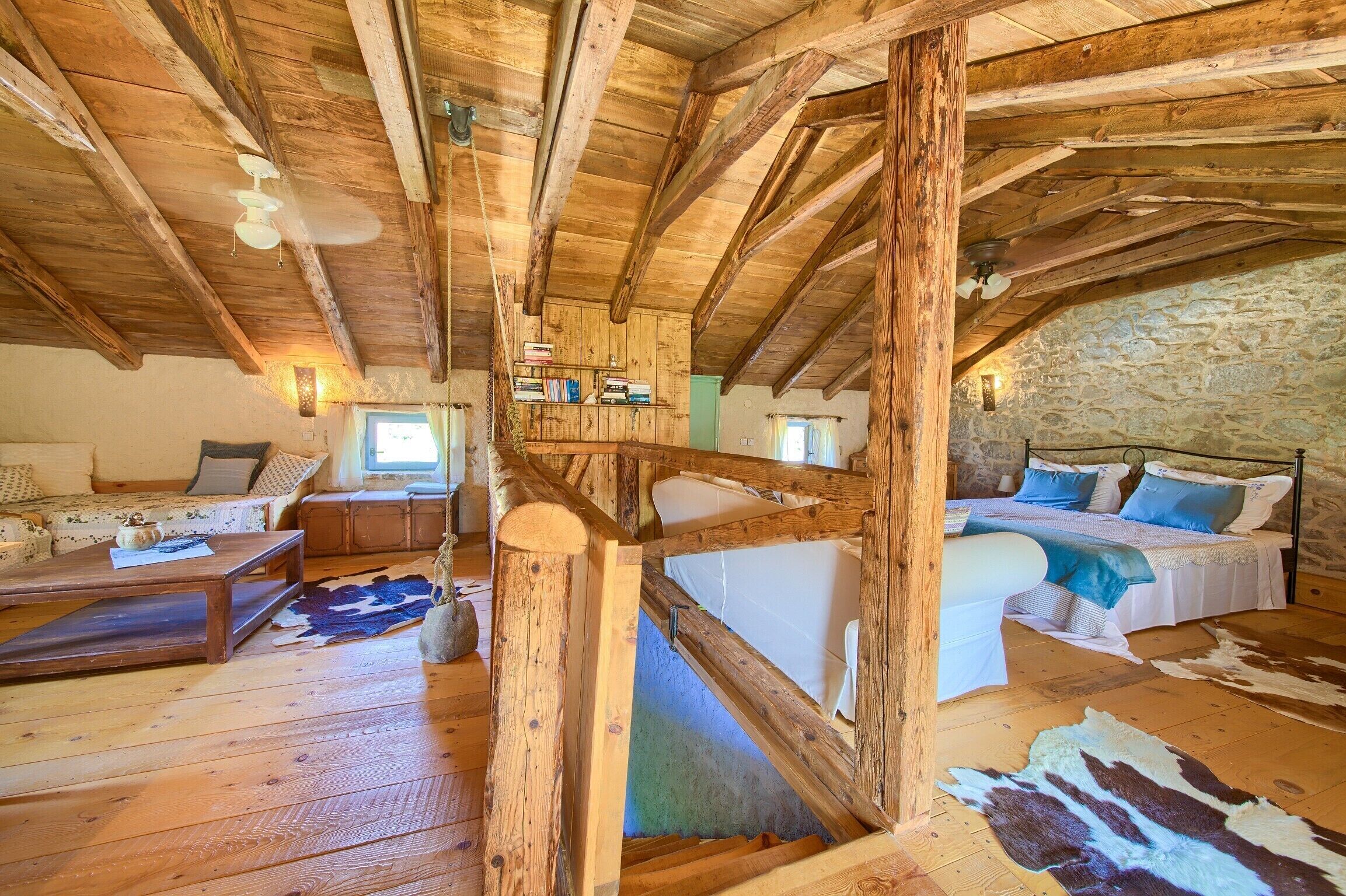 Een rustiek houten interieur met een slaapverdieping, een bank en een eethoek.